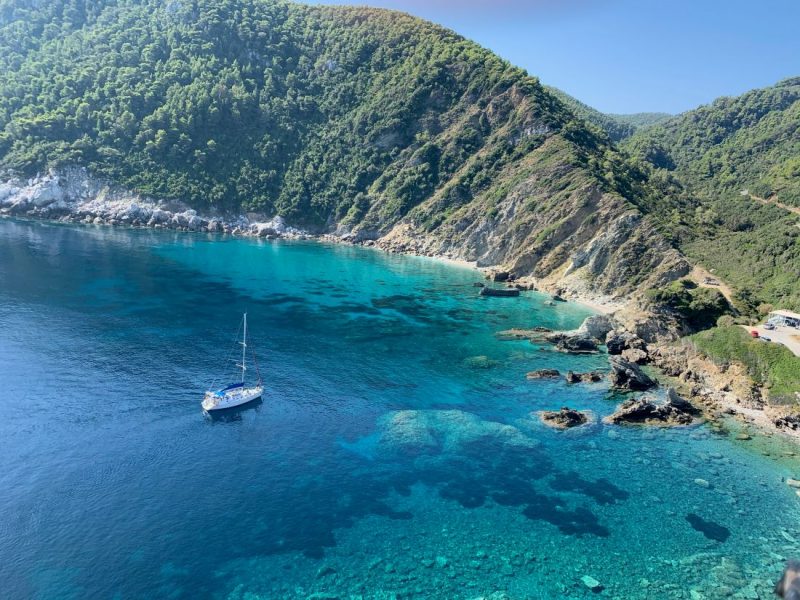 A boat sailing on a turquoise sea, with cliffs. 