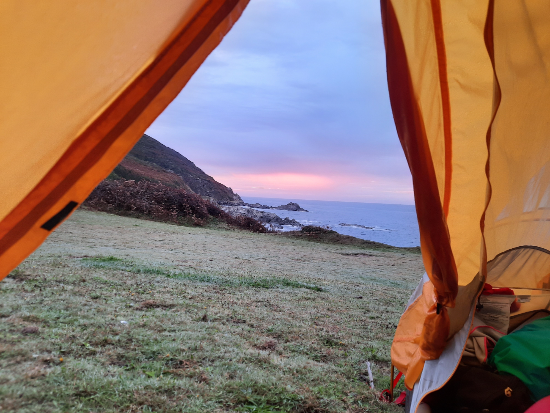 View through an open tent of a sunset over the sea