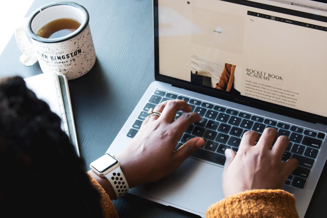 A woman's hands typing on a laptop keyboard